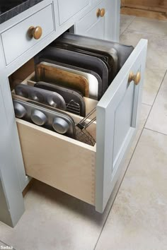 an open drawer in the middle of a kitchen with dishes and utensils inside