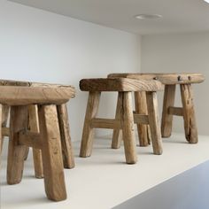 three wooden stools sitting on top of a white counter