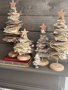 three small wooden christmas trees sitting on top of a mantle next to a pile of books