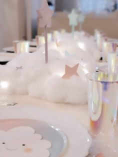 the table is set with white plates and silver cups, stars on top of fluffy clouds