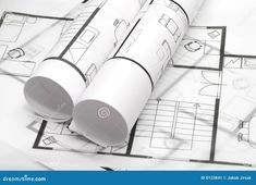 two rolls of architectural paper on top of blueprints and plans for a house