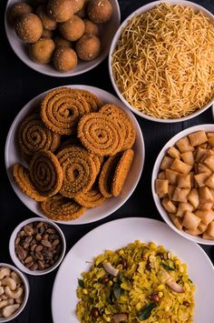 bowls filled with different types of food on top of a black table next to nuts and other foods