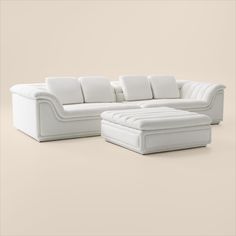 a white sectional sofa with pillows on it and a footstool next to it