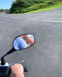 a person on a motorcycle taking a photo in the side mirror