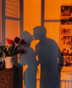 the shadow of a man and woman kissing in front of a wall with pictures on it