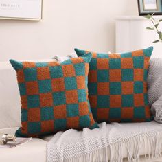 two orange and green pillows on a white couch