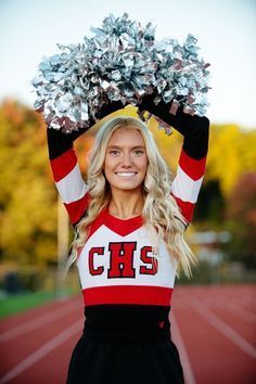 a cheerleader holding her pom - poms in the air