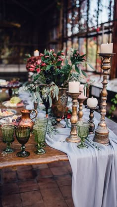 a table topped with lots of vases filled with flowers and candles next to each other