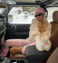 a woman sitting in the back seat of a car wearing pink socks and a knitted hat