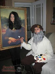 a man with long black hair and beard holding a paintbrush in front of a painting