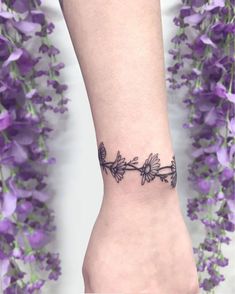 a woman's foot with a tattoo on it and flowers in the back ground