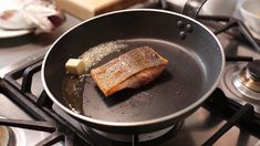 a fish is cooking in a frying pan on top of the burner stove