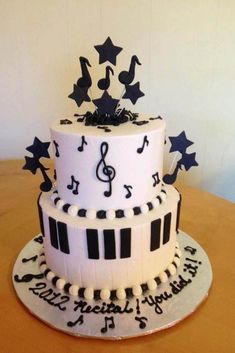 a three tiered cake with musical notes and stars on the top is decorated in black and white