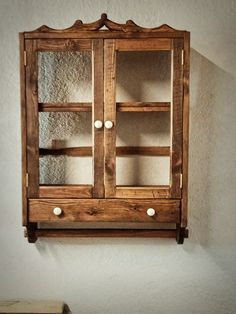 a wooden cabinet with glass doors hanging on the wall