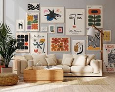 a living room filled with lots of art on the wall above a white couch and wooden coffee table