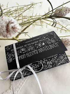 a black and white wedding card tied to a twig with twine on it