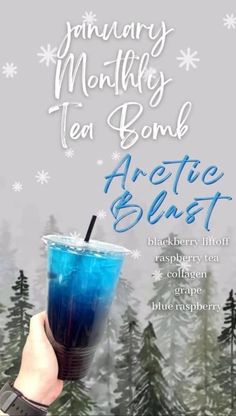 a person holding up a blue drink in front of snow covered trees and the words arctic blast