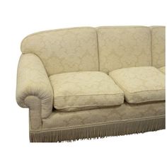 a beige couch with fringe trim on the armrests and back ends, sitting in front of a white background