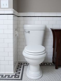 a white toilet sitting in a bathroom next to a wooden cabinet and tiled flooring