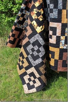 two quilts hanging from a clothes line in the grass