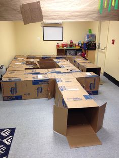 cardboard boxes are stacked on the floor in an empty room with a projector screen