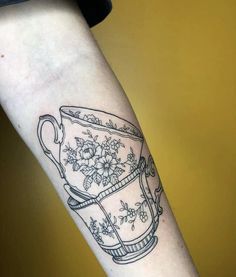 a tattoo on the arm of a woman with a tea cup and flowers in it