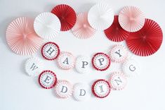 red and white paper fans with the words happy wedding spelled out on them are arranged in a heart shape