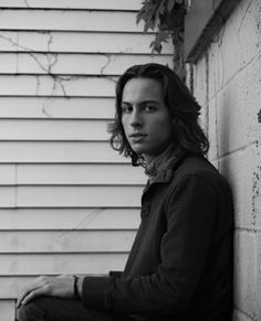 black and white photo of a man leaning against a wall