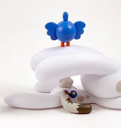 a blue and white bird figurine sitting on top of a white object that looks like it is floating in the air