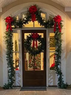 the front door is decorated with christmas wreaths and red bows