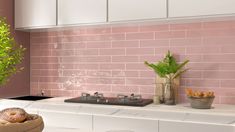 a kitchen with pink tiles on the wall and counter tops, potted plants in front of the stove