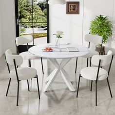 a white table with four chairs and a potted plant in the corner next to it