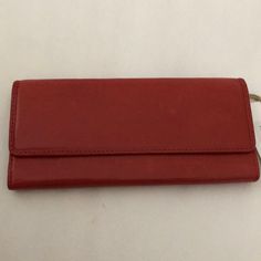 a red leather wallet sitting on top of a white table next to a pair of scissors