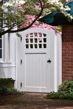 an open white door on the side of a brick building next to a flowering tree