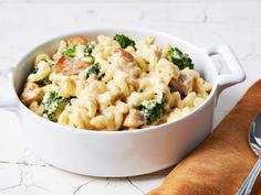 a white bowl filled with macaroni and broccoli on top of a table