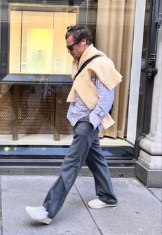 a man is walking down the sidewalk in front of a store window with his back to the camera