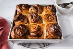 a pan filled with cinnamon rolls next to a cup of coffee