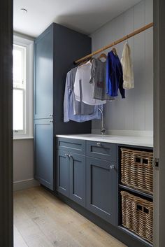 a laundry room with blue cabinets and hanging clothes