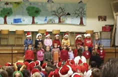 a group of children in santa hats standing on stage