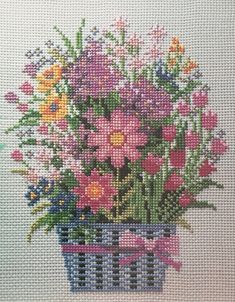 a cross stitch picture with flowers in a basket