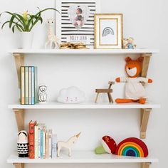 three white shelves with toys and pictures on them