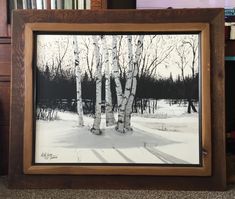 a black and white photo of birch trees in the snow by a bookshelf