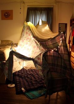 a tent is set up in the middle of a room with other items on the floor