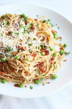 pasta with peas, bacon and parmesan cheese on a white plate for garnish