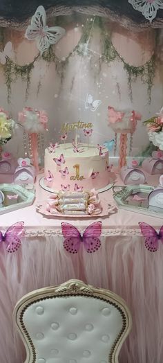 a birthday cake on a table with pink and white decor in the background, surrounded by butterflies