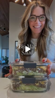 a woman with glasses is holding up a plastic container filled with salad and lettuce