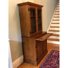 a wooden cabinet sitting in the corner of a room next to a stair case and rug