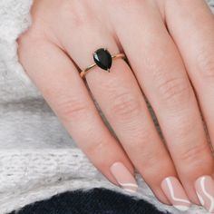 a woman's hand with white and black nail polish holding a ring on her finger