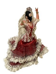 a figurine of a woman dressed in red and white with her arms outstretched