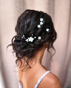 the back of a woman's head with hair pins in her hair and flowers in her hair